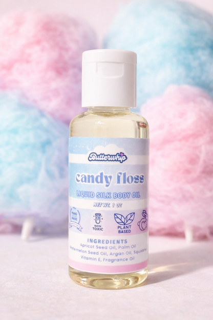 1 oz Bottle of vanilla cotton candy scented liquid silk body oil with cotton candy in the background
